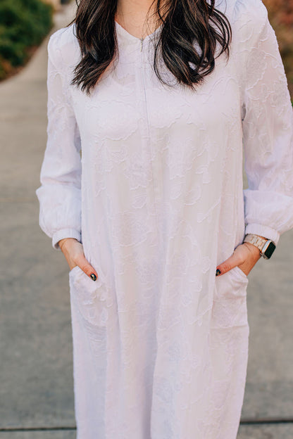 Long white dress with floral appliques and zipper front.