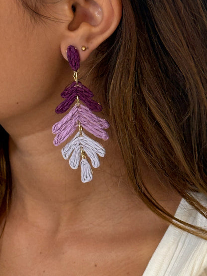 A pair of purple ombre cascading leaf earrings with gold accents on a model