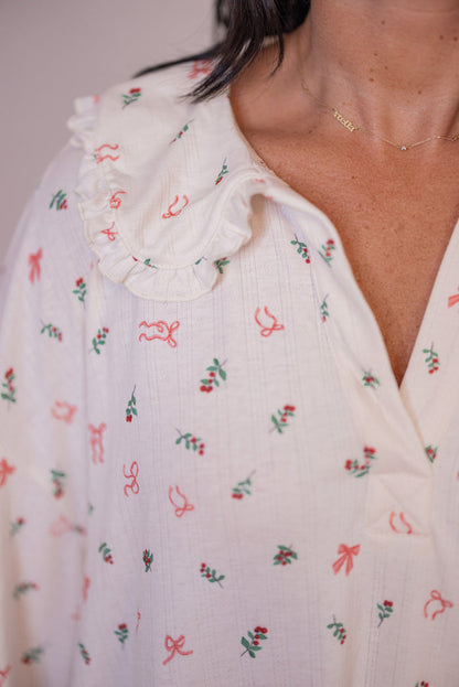 Women's cream pointelle knit pajamas with red, pink and green holly and bow tie print by Peach Love California showing ruffled collar