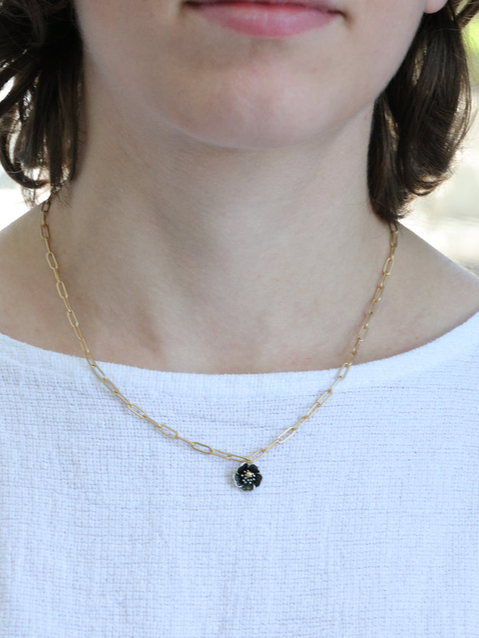 Close-up of a woman wearing a matte gold necklace with a small five-petal flower pendant – minimalist floral jewelry by Ardor Boutique