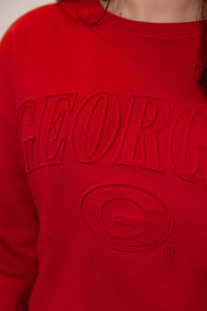 Women's red terry knit sweatshirt with embossed 'Georgia' in center by Gameday Social showing up close view of embossed lettering