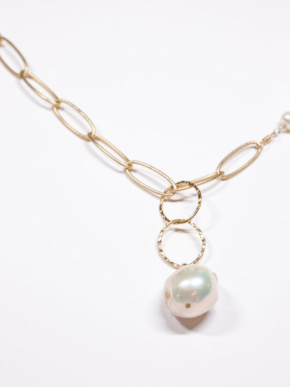 Close-up of the Grace Pearl NH Necklace from Ardor Boutique, featuring a matte gold link chain, hammered rings, and a large baroque freshwater pearl drop.