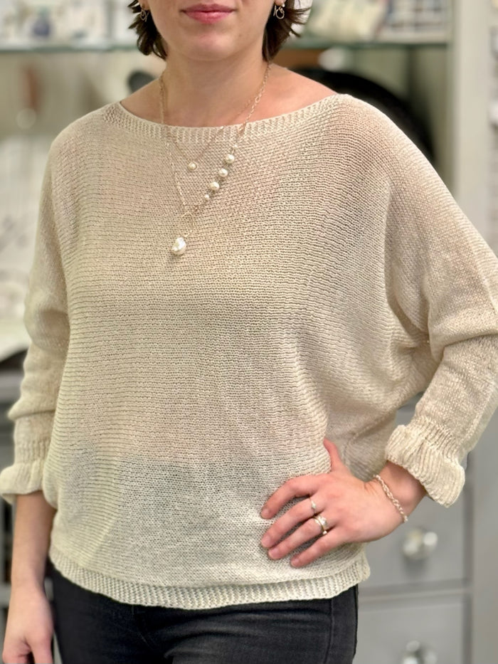 nh Layered rose gold pearl necklaces styled with beige sweater