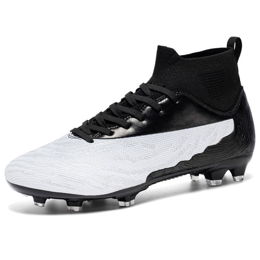 Top-down flat lay of outdoor football boots on green turf with ball partially in frame