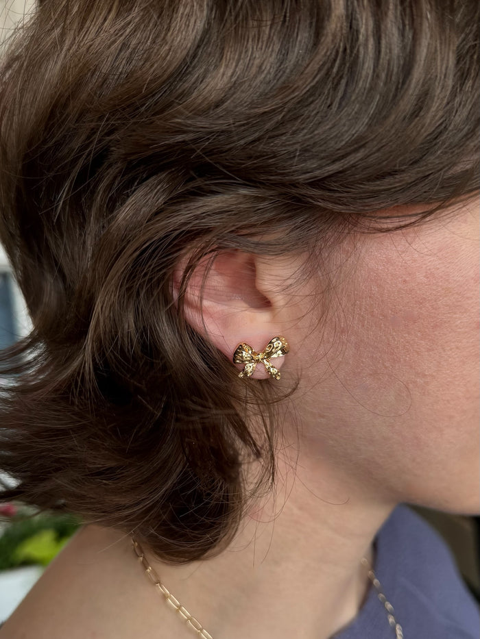 woman wearing gold bow earring